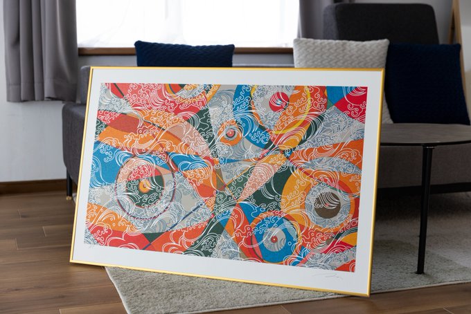 A colorful abstract framed artwork featuring swirling wave-like patterns in red, blue, orange, and white is displayed on the floor of a modern living room with a gray sofa.