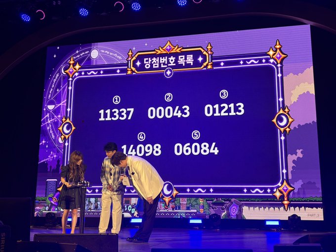 The image captures the final lucky draw at #KBW2026, with five winning numbers (11337, 00043, 01213, 14098, 06084) displayed on a large purple screen labeled "당첨번호 목록" (Winning Number List) while three hosts stand on stage to announce the results to the audience.