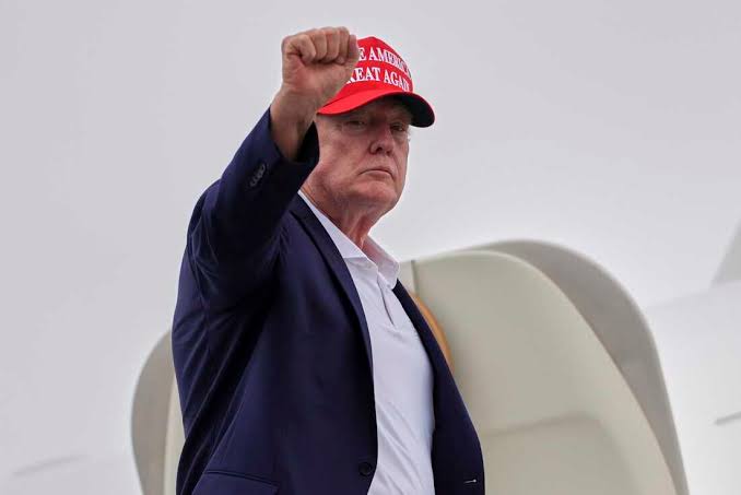 Donald Trump raises his fist while wearing a red "Make America Great Again" hat, relating to the rumors of a Trump token ($TRUMP, $WWW) gaining traction in the crypto world.