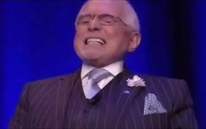 An older man in a pinstripe suit and glasses laughs heartily with his eyes closed on a stage with a blue background. The image appears to relate to the post's comparison between Chainlink ($LINK) and a different "LAYER" cryptocurrency, possibly showing amusement at the comparison or the project's branding.
