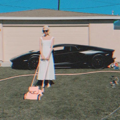 A woman in a white dress and sunglasses pushes a pink lawnmower across a grassy lawn, standing in front of a black sports car parked near a garage.