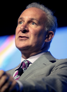Peter Schiff, dressed in a gray suit and pink striped tie, speaks at an event while criticizing Michael Saylor, arguing that Strategy's potential collapse could damage Bitcoin and crypto more than FTX's downfall.