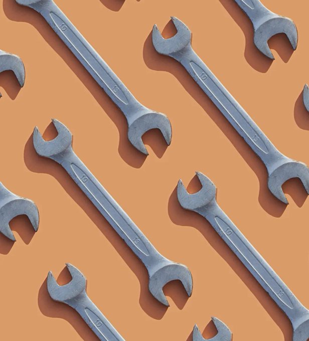 A pattern of metallic open-end wrenches arranged diagonally on a brown surface.