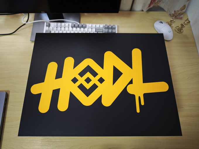 A black mat on a desk displaying a stylized yellow graffiti-style 'HOWL' logo, positioned in front of a mechanical keyboard and computer monitor.