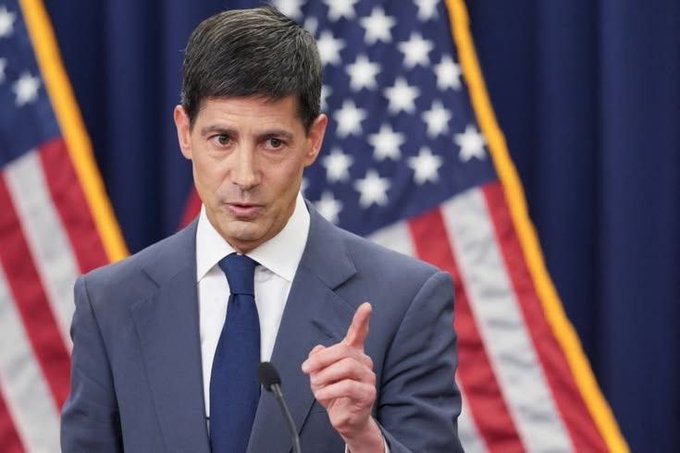 A man in a dark suit and blue tie speaks at a podium with two American flags in the background, gesturing with his index finger raised—suggesting an official making an important statement, fitting the post's context of an upcoming US CPI data release that could trigger market volatility.