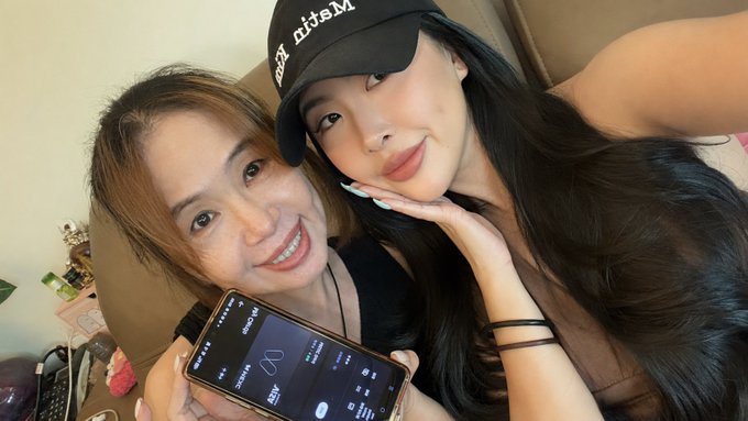 A selfie of two smiling women, one wearing a 'Matrix Port' cap, with one holding a smartphone displaying an app with the text 'Matrixport' visible.