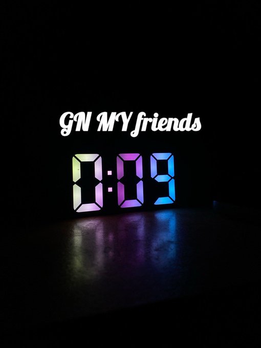 A digital clock glowing in the dark displays the time '8:09' in colorful rainbow LED numerals, with the text 'GN MY friends' written above it.