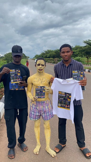 Three young men pose on a roadside, with the central figure covered in gold body paint displaying "CABS" on his chest, all holding promotional flyers for "CABS Future Insurance Brokers Ltd" featuring cryptocurrency logos including Bitcoin and XRP. The image supports the caption by showcasing the eye-catching, attention-grabbing guerrilla marketing tactic designed to make the "pumpcade" promotion go viral on social media.