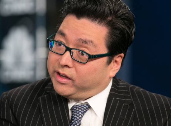 A man wearing glasses and a pinstripe suit is shown in what appears to be a news interview setting with a blue background.