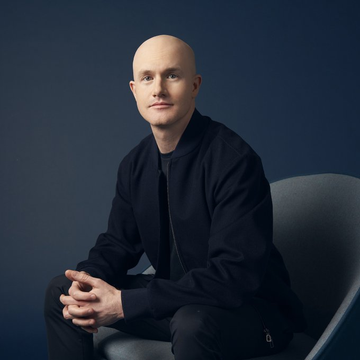 Brian Armstrong, the bald CEO of Coinbase, is pictured seated in a dark jacket with his hands clasped, fitting the context of his recent comments on potential SEC and CFTC regulations that could supplant the CLARITY Act.