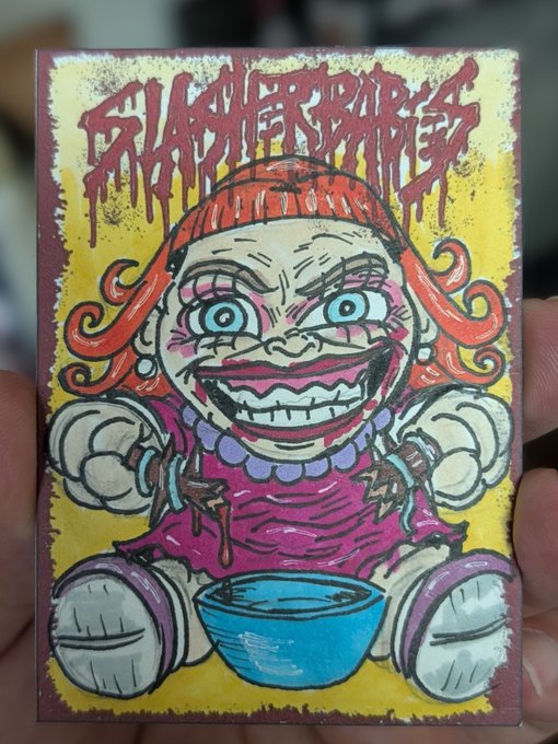 A hand holding a colorful, hand-drawn trading card featuring a creepy doll-like character with the text 'BLACKBERRY'S NIGHTMARE' in red dripping letters.