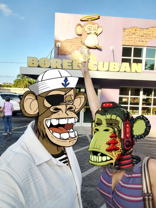Two cartoon ape characters—one wearing a sailor hat and the other in a cybernetic helmet—pose in front of a building displaying a monkey mural and the text "BOREE CUBAN," with the real-life mural behind them matching the Bored Ape aesthetic celebrated in the caption "Apes in Miami doing ape shit!"