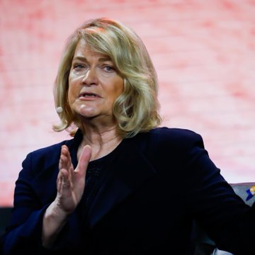 A blonde woman in a dark blazer, likely Senator Cynthia Lummis, speaks with an expressive hand gesture against a reddish backdrop, illustrating the post's call to action supporting the passage of the Clarity Act during the August recess.