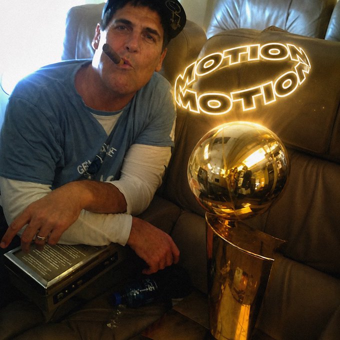 A man wearing a cap and smoking a cigar sits on a leather couch beside a golden basketball trophy displaying "MOTION MOTION" on its backboard, humorously presenting the trophy as the "asset class" referenced in the post about motion becoming the new crypto.