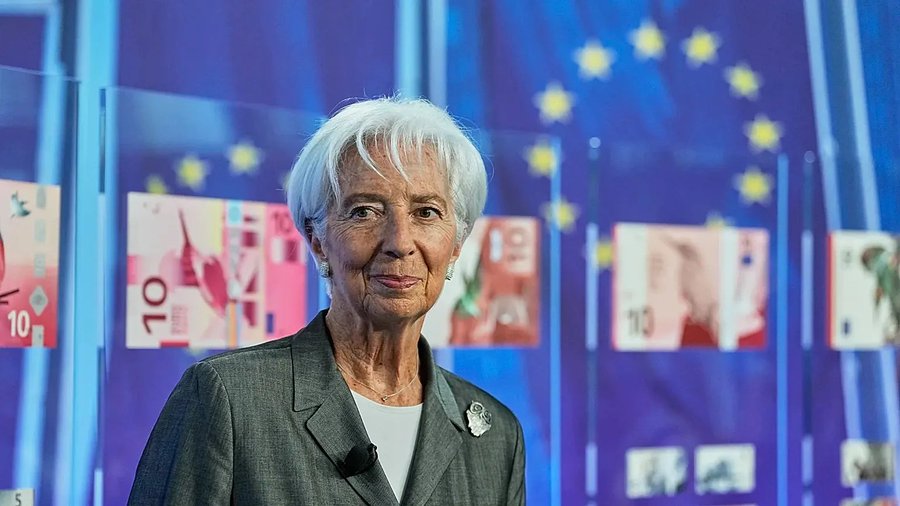 Christine Lagarde, President of the European Central Bank, stands before displays of euro banknotes and EU stars, visually connecting her to the post's report about her intervention to delay Binance's Greek MiCA licence over concerns that the crypto exchange could expand dollar stablecoin use and undermine the digital euro.