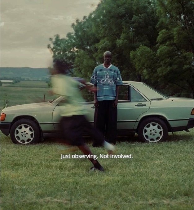 A man stands calmly in front of a vintage green car with the caption "Just observing. Not involved." as another figure runs past in a blur, with the watermark @olan.diaz visible in the corner. The image's theme of a quiet bystander watching someone rush by mirrors the post's message about pausing to observe the full scope of @wolfswapdotapp beyond just token swapping.