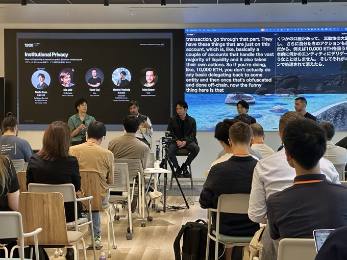 A panel discussion titled 'Institutional Privacy' at a conference, featuring speakers Tohru Daito, Nic Jubb, Brad Gai, Masuk Yoshida, and Matt Crowe, with a large screen displaying Japanese text about Ethereum transactions.