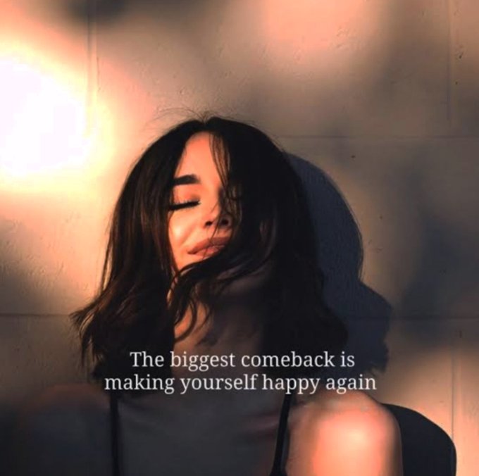 A woman with long dark hair stands with her eyes closed against a wall, illuminated by warm light, with the text 'The biggest comeback is making yourself happy again.'
