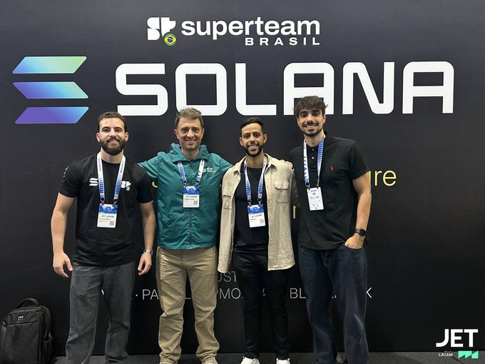 Four men posing for a photo in front of a black backdrop with 'superteam BRASIL' and 'SOLANA' branding.