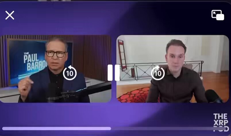 The image shows a screen displaying two men talking to each other, with one man wearing glasses and the other wearing a brown shirt. The background of the image features a purple wall with a television mounted above it. There are also some numbers visible on the screen, which could be related to the content being discussed during their conversation or possibly used for timing purposes.