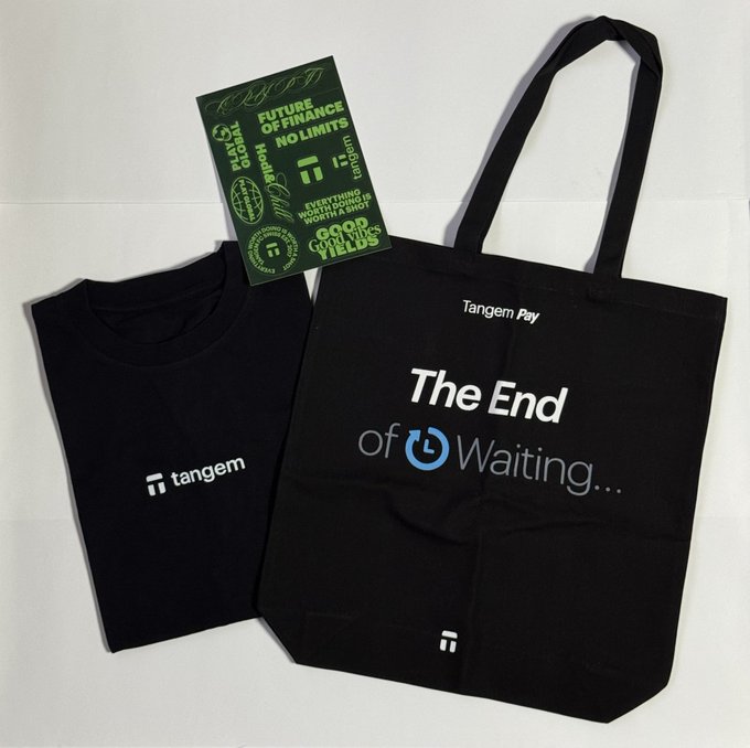 A black Tangem-branded t-shirt and tote bag featuring "Tangem Pay" and the slogan "The End of Waiting..." are displayed alongside promotional stickers for the "Future of Finance No Limits" event held by Tangem and TAKOBAR. The image showcases the merchandise given out at the event mentioned in the post, including the sticker that reads "Everything Works Stand Up Worth a Speech."