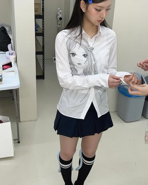 A young woman models a white long-sleeved button-up shirt featuring a pencil sketch-style anime girl print, paired with a navy pleated mini skirt and knee-high socks, fitting the "archv sol" aesthetic post. She stands indoors, looking down as hands appear to adjust her sleeve.