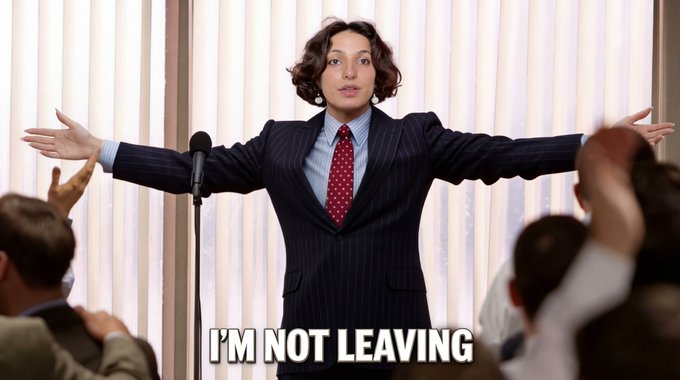 The image features a woman standing up, wearing a suit and tie, with her arms outstretched as if she's giving a speech or making a public announcement. The caption of the image reads "I'm not leaving", which seems to be a reference to the popular social media account @MedusaOnchain. The post also mentions that someone has been using the name @MedusaOnchain, possibly indicating an ongoing conversation or interaction related to the account.