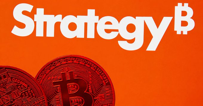 In this image, a pair of red Bitcoins are positioned next to each other, with the larger one on top of the smaller one. The background color is orange. The main elements present in the image are the two Bitcoins, which appear to be related to the topic of cryptocurrency or digital assets, and the text "Strategy" written above them. This suggests that they may be discussing strategies for investing in Bitcoin or other cryptocurrencies, possibly aiming to make a profit from their purchase.