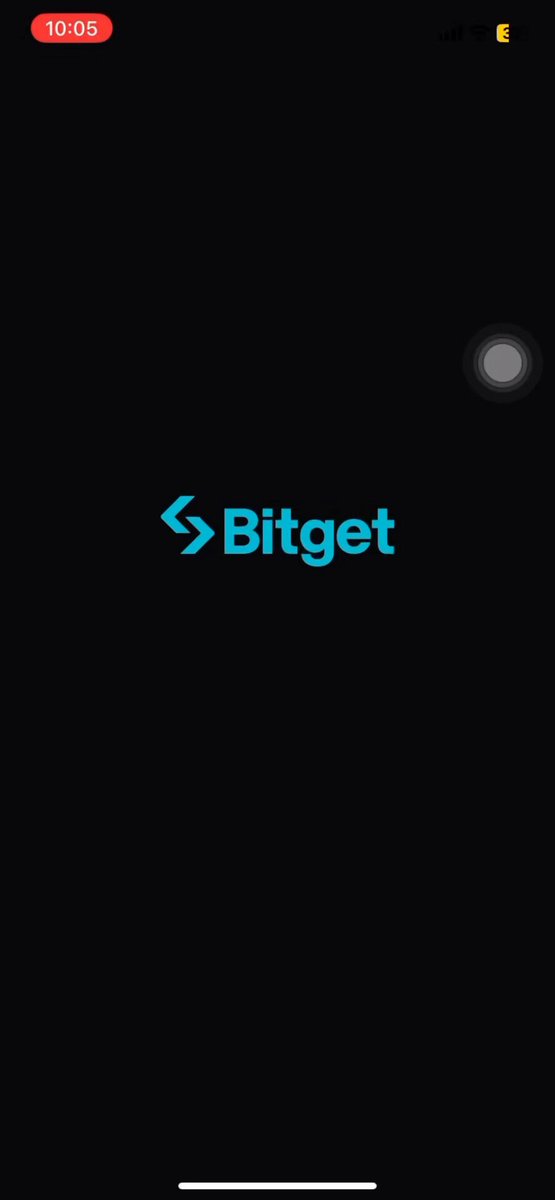 The image shows a black cell phone screen displaying the Bitget app logo, which is blue with white text. The background of the screen is dark gray, making the logo stand out prominently. The app's name "Bitget" is displayed at the top left corner and the word "BGB" can be seen in the center. The bottom right corner features a small image of a person holding a cell phone.