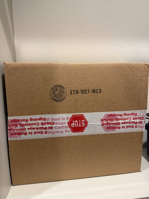 A sealed brown cardboard box bears a University of Michigan seal and the label 'ETB-10CT-MC3', sealed with red 'STOP' tape warning that the seal is broken if the package is damaged.