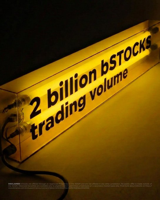 A glowing yellow fluorescent light tube displays the text "2 billion bSTOCKS trading volume," visually amplifying the caption's celebration of Binance's weekend trading milestone.