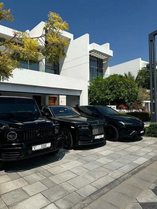 Three luxury vehicles—a black Mercedes-AMG G-Wagon (Dubai plate 3358), a black Rolls-Royce (Dubai plate 67728), and a black Porsche—are parked outside a modern white villa, symbolizing the wealth and status-driven culture that the post critiques regarding Web3's farming mindset.