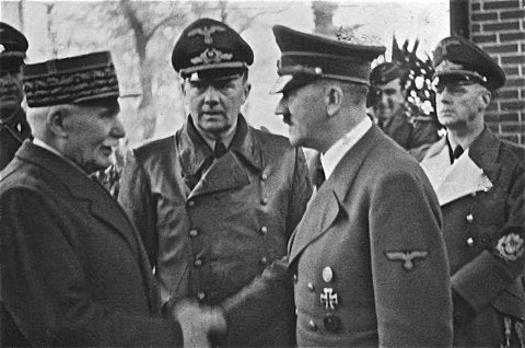 A black and white photograph showing Adolf Hitler shaking hands with a French official, observed by other military officers in uniform. The image contrasts with the post's discussion about French-speaking figures (Jean Meyer, Damien Patureaux, Pierre Morizot) preparing for an inevitable outcome through collaboration rather than confrontation.