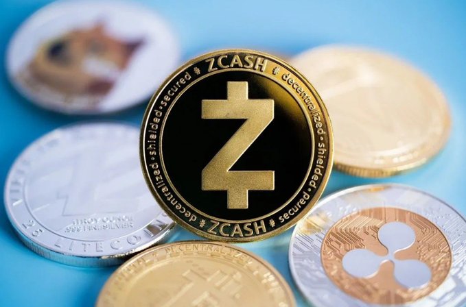Close-up of various cryptocurrency coins, with a central ZCASH (Z) coin surrounded by Litecoin and Ripple (XRP) coins on a blue surface.