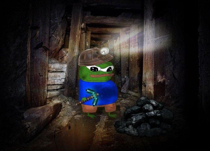 A Pepe the Frog meme edited as a miner wearing a hard hat with a headlamp and holding a diamond pickaxe, standing next to a pile of coal in a dark mine shaft.