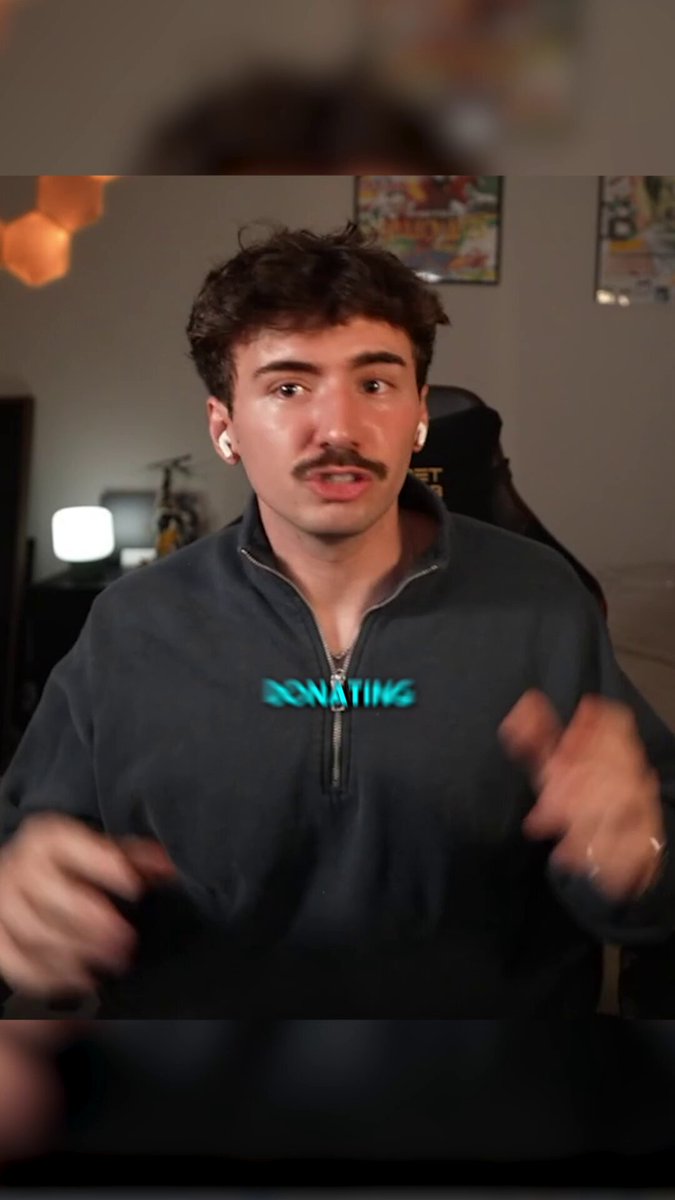 The image features a man wearing a black sweatshirt with the word "Donating" written across his chest, who appears to be making a funny face for the camera while sitting in front of a computer screen. The caption below the photo reads, "If the coin skyrockets you guys saved me & my kids life". This post seems to be about a streamer named @YahsLion and he's been targeted by trolls who have posted negative comments on his account.