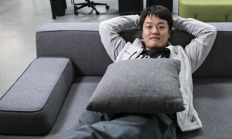 Hidetaka Miyazaki, the creator of video games like Elden Ring and Dark Souls, reclines comfortably on a gray modular sofa with his hands behind his head, holding a gray cushion on his lap.