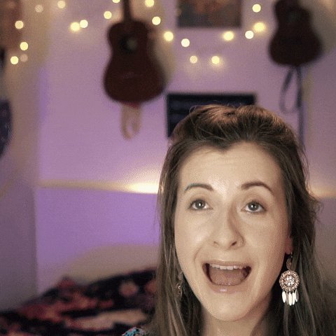 In this image, a woman with long brown hair is shown making a funny or surprised face for the camera, as if she has been called upon by someone. She appears to be laughing or showing an unexpected reaction. Her outfit consists of a shirt that features white polka dots and hoop earrings, adding to her overall playful appearance. 

The background includes guitars hanging on the wall, giving off a musical vibe, which complements the woman's attire. The image contains multiple "karma loops" or repetition effects in various areas, emphasizing the idea of something being called upon repeatedly.
