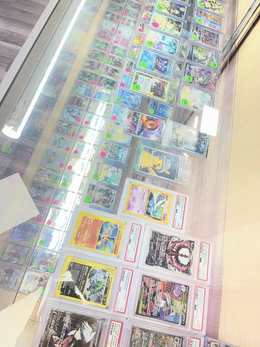 A glass display case filled with numerous Pokémon trading cards arranged in rows, with various holographic and rare cards visible.