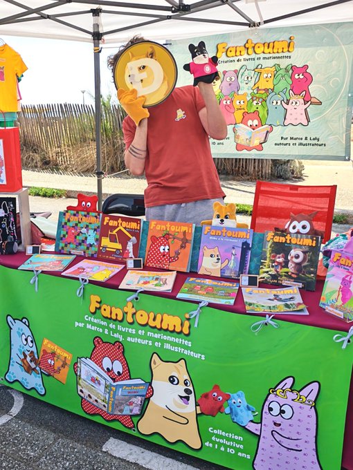 A vendor stall for 'Fantoumi,' a children's book and marionette collection by Marex & Laly, featuring colorful monster character artwork and books on display.