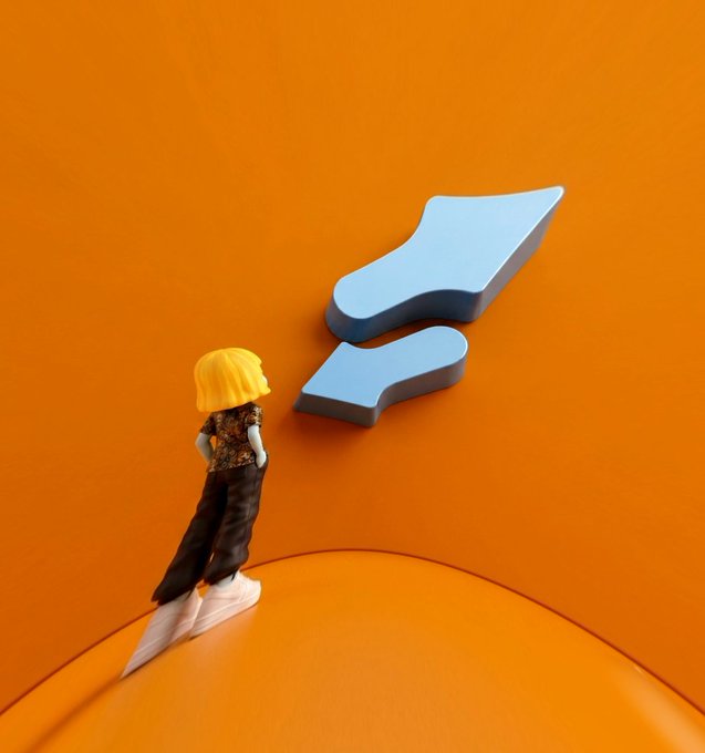 A small figurine with blonde hair and a floral shirt stands on an orange curved surface, gazing up at a large light blue 3D logo or shape.