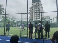 People play soccer on an enclosed turf field surrounded by city buildings, with several players in athletic gear gathered on the field and sidelines. The image captures a casual sports meetup, likely connecting to the post about meeting a boss and the founder of @paj_cash, possibly during a networking or recreational event in an urban setting.