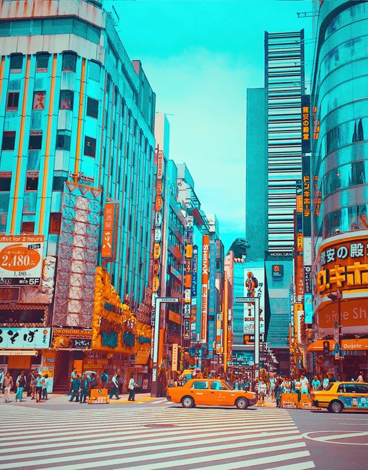 A vibrant, teal-and-orange stylized photograph of a busy city street, likely in Japan, featuring taxis, pedestrians, tall buildings, and numerous illuminated signs with Japanese text.