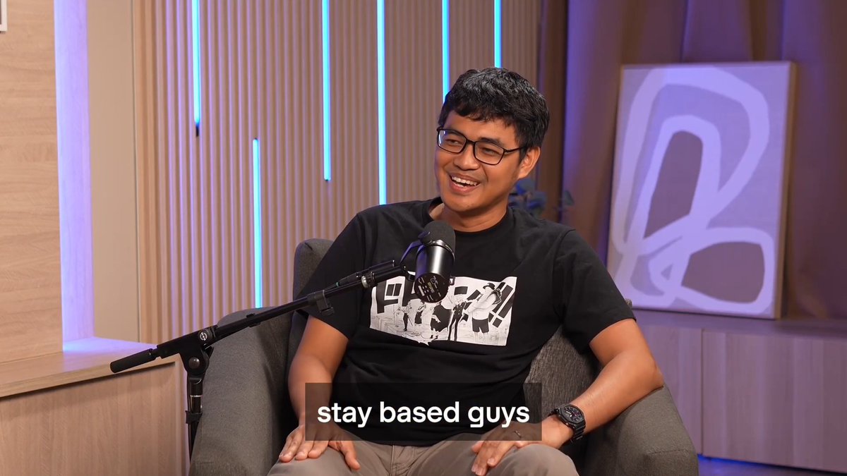 A man wearing glasses and a black graphic t-shirt laughs in a podcast studio, with the caption "stay based guys" displayed below, complementing the post celebrating Kevin's "zero to one" journey on the GitLawb podcast.