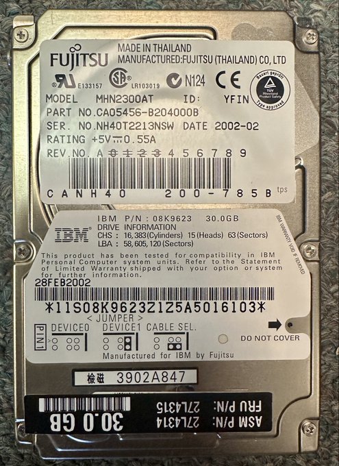 A vintage 2.5-inch Fujitsu hard drive manufactured in Thailand, model MHN2300AT, with 30.0GB capacity, manufactured for IBM in February 2002 (DATE 2002-02). The label shows specifications including 63 sectors, 15 heads, 16,383 cylinders, and IBM part number 08K9623.