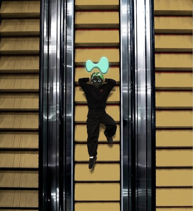 A person lies on their back between two escalators, hands behind their head, wearing a black outfit and an anime-style mask, while a small green Care Bear plush floats above them. The relaxed, playful pose and "Gm CT Happy Sunday" caption suggest a carefree, weekend crypto-community vibe shared from Connecticut.
