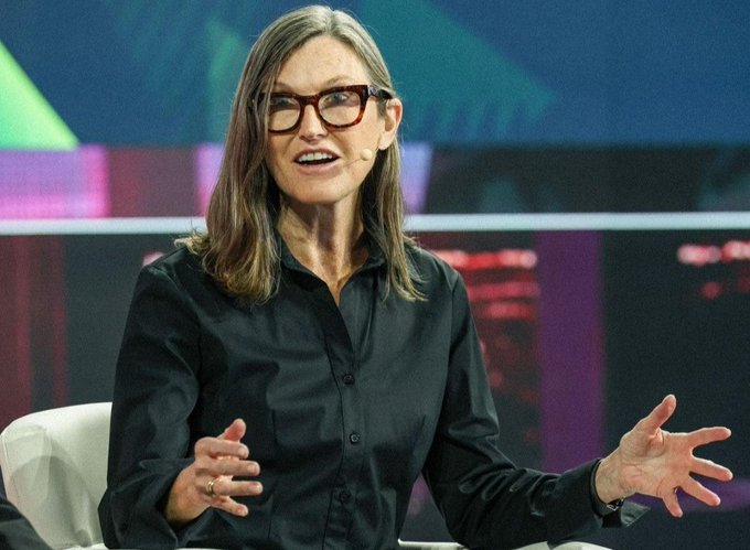 The post appears to be cut off, but based on the visible text, it discusses ARK Invest's expanded position in Circle (likely CRCL), reflecting institutional confidence in crypto infrastructure. The image shows a woman with long brown hair, wearing black-framed glasses and a black button-down shirt, speaking expressively with her hands open at what appears to be a conference or panel discussion—likely depicting an ARK Invest executive or industry figure discussing the digital asset investment thesis referenced in the text.