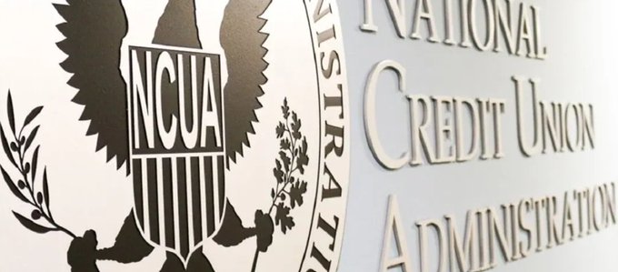 The image shows the official emblem and signage of the **National Credit Union Administration (NCUA)**, featuring an eagle with a shield displaying "NCUA" alongside the agency's full name in raised lettering. It visually reinforces the post's message about the NCUA's recent regulatory update, specifically the removal of the outdated Credit Union Service Contracts provision (12 CFR 701.26) to ease compliance for credit unions.