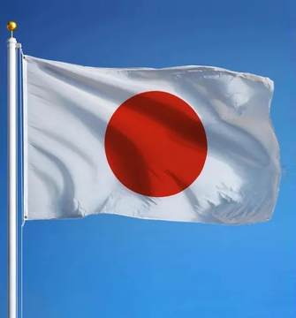 The Japanese flag waves against a blue sky, symbolically representing Japan as the Tokyo-based company Metaplanet prepares to raise $328M through yen-convertible bonds to fund share buybacks and debt repayment. The flag's prominence underscores the Asian market origins of this capital raise, which will test investor appetite across both European and Asian markets.