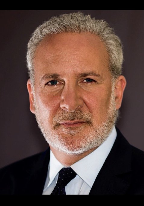 A professional headshot of a gray-haired, bearded man in a dark suit and tie.